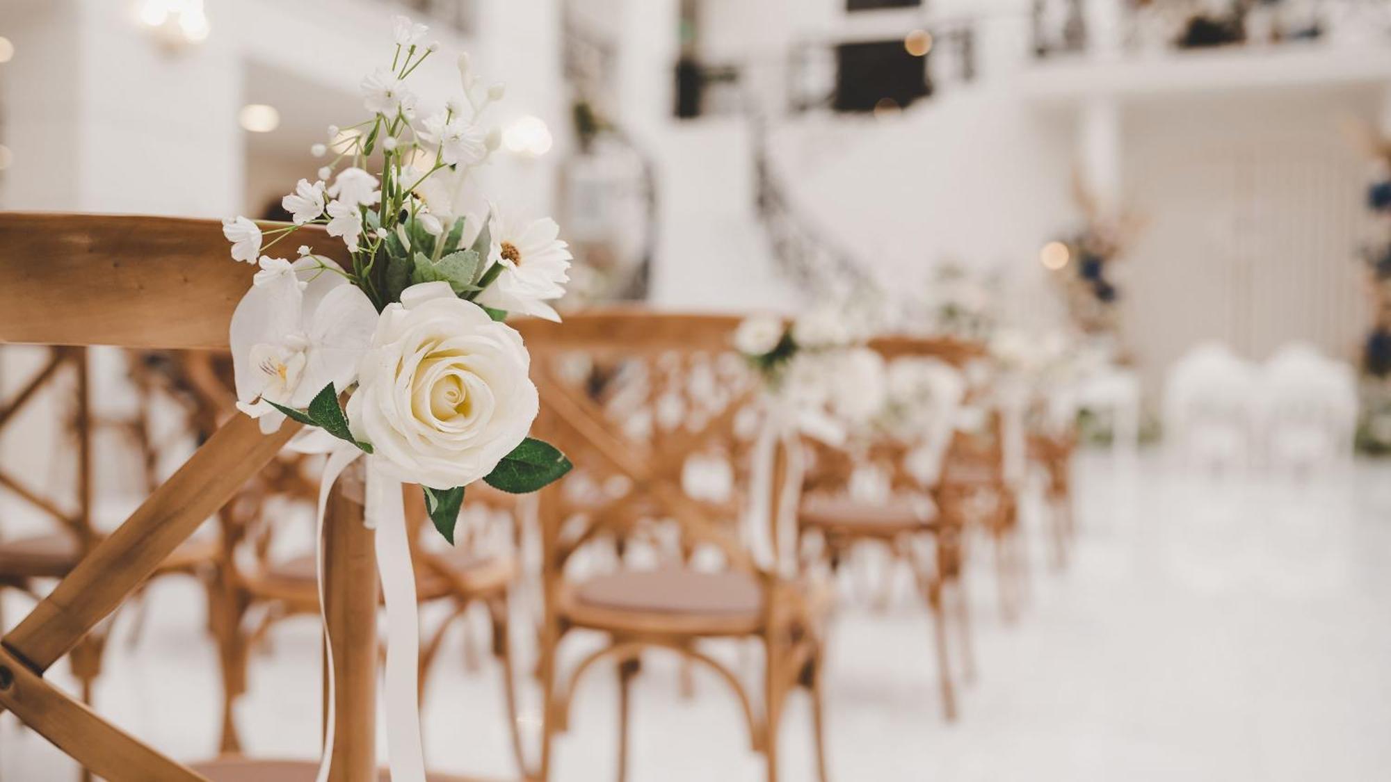 Intercontinental Dar Al Iman Madinah By Ihg Hotel Medina Eksteriør billede The photo showcases a beautifully arranged event space, likely set up for a wedding or special occasion. In the foreground, wooden chairs are neatly lined up, some adorned with decorative floral arrangements. The flowers include white roses and small