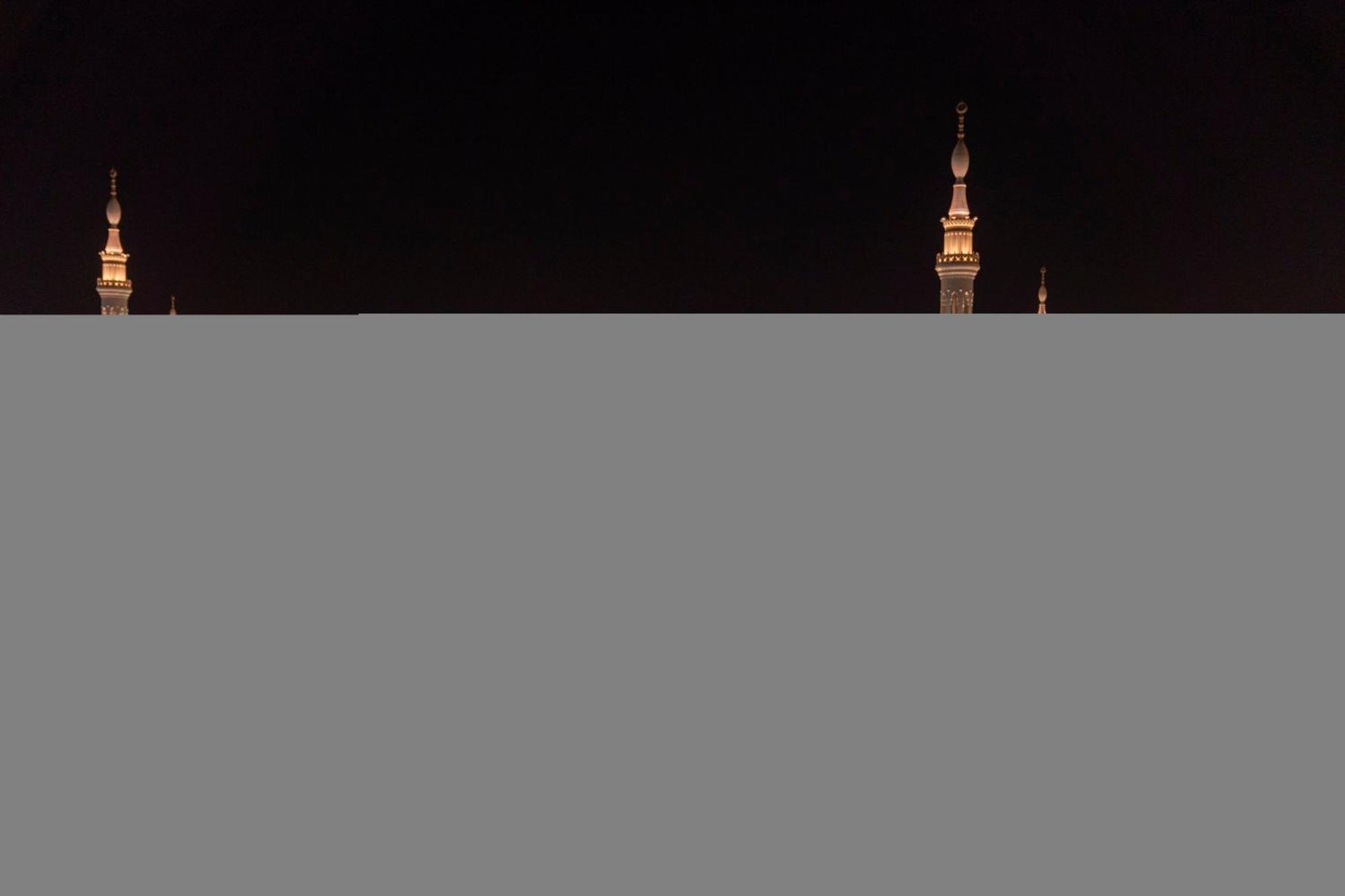 Intercontinental Dar Al Iman Madinah By Ihg Hotel Medina Eksteriør billede The image appears to show a night scene featuring tall structures with pointed tops, likely minarets, illuminated against a dark background. The lighting creates a striking contrast, highlighting the architectural details of the structures. The overa