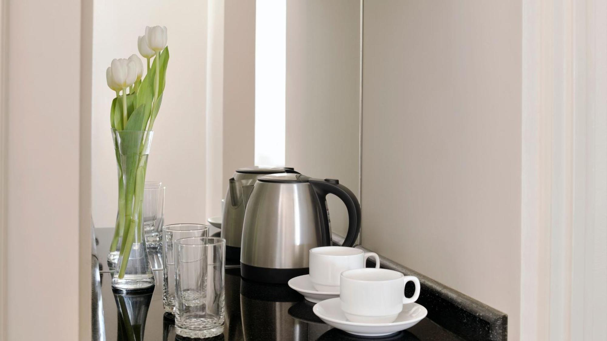 Intercontinental Dar Al Iman Madinah By Ihg Hotel Medina Eksteriør billede The photo depicts a neatly arranged beverage area. In the foreground, there are two white coffee cups on small saucers. Next to them, there are two clear drinking glasses. In the background, there is a silver electric kettle, which is positioned next