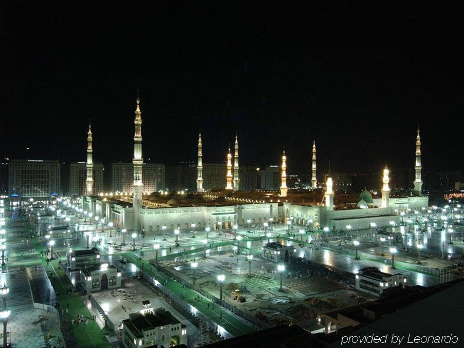 Intercontinental Dar Al Iman Madinah By Ihg Hotel Medina Bekvemmeligheder billede The image shows the illuminated landscape of a mosque complex at night. It features several tall minarets, which are typically part of Islamic architecture, adorned with lights. The mosque's central building is also brightly lit, surrounded by an ope