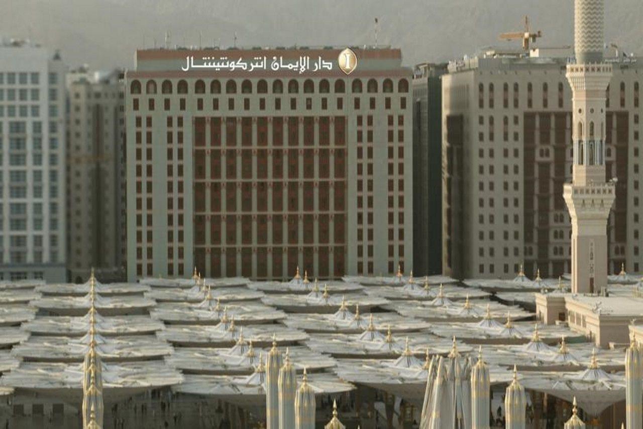 Intercontinental Dar Al Iman Madinah By Ihg Hotel Medina Eksteriør billede The photo shows a view of a large building with a modern architectural design, which appears to be a hotel or a commercial establishment. In front of the building, there are several large white canopies that provide shade, likely in a public space or